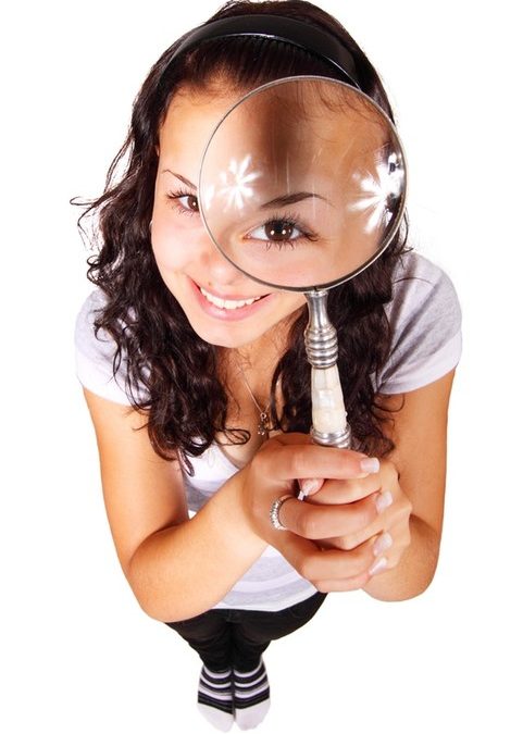 Photo of young woman looking into magnifying glass